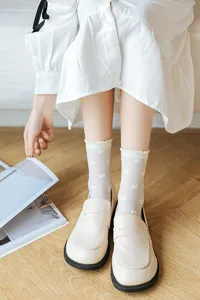 White crew socks detail featuring cute bow patterns, paired with classic loafers for a sweet look.