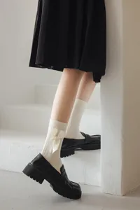 Vue détaillée de chaussettes Lolita blanches mi-mollet ornées d'un nœud en satin et d'une perle.