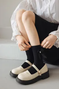 Détail de chaussettes Lolita noires avec nœud mignon et perle pour style adorable.