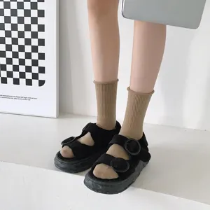 Vue détaillée de chaussettes côtelées marron associées à des sandales à plateforme noire.