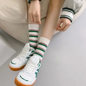 Detailed view of women striped mid-calf socks paired with stylish green and white sneakers.