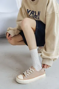 Detailed view of white cotton mid-tube socks with delicate pattern worn by model in outfit.