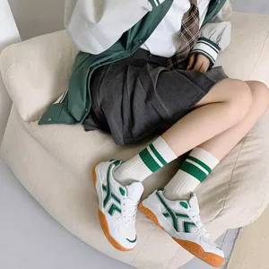 Detailed shot of striped tube socks paired with retro sneakers and pleated skirt, perfect style.