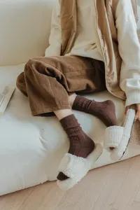 Cozy brown wool slouch socks paired with fluffy plush slippers for a warm, stylish look.