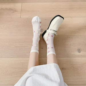 Detail view of sweet white Japanese style mid-calf socks with cute bow and flower prints.