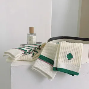 Detailed shot of Japanese style women mid-tube socks featuring green clover embroidery stripes.