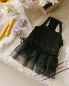 Detail shot of black pet dress with lace ruffles, elegant floral and candle background setup.