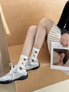 Detail view of cute Japanese style mid-calf socks with heart pattern worn with silver sneakers.