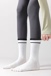 Detailed view of white split-toe yoga socks with black stripes and non-slip silicone grip.