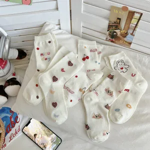 Close-up detail view of cute Japanese style white mid-tube socks featuring adorable cat and bear embroidery.