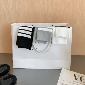 Close-up detail of Japanese JK style striped mid-calf socks displayed neatly on a paper bag.