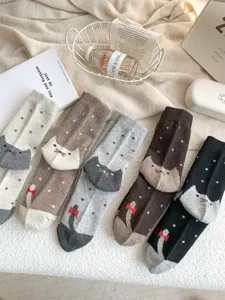 Vue détaillée de chaussettes en laine à motif chat et pois dans un décor douillet.