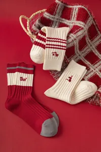 Detailed view of red mid-tube knit socks featuring Year of the Snake embroidery and ribbed cuffs.