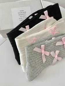 Close-up of sweet Japanese style mid-tube socks with cute pink bowknot details in assorted colors.
