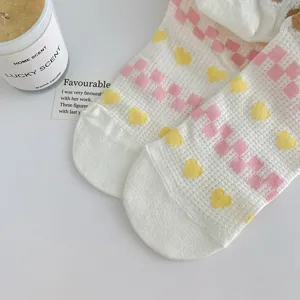Cute women's white mid-calf socks featuring pink checkerboard and yellow heart mesh pattern.
