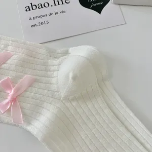 Detailed view of white Lolita socks with pink bows and soft ribbed knit texture.