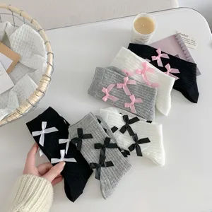 Ribbed mid-tube socks featuring sweet bows, showing delicate knit texture and fine details.
