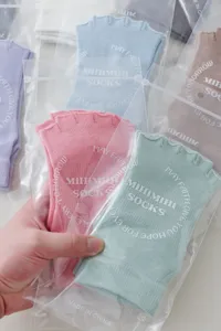 Detailed view of pastel toeless five-finger yoga socks in transparent packaging bags.