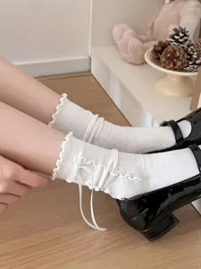 Close-up detail of white ruffled crew socks featuring a sweet ribbon bow for sweet lolita style.