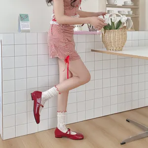 Detail shot of women lace ruffle stack socks paired with red flat shoes in a clean room.