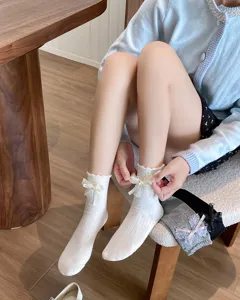 Close-up detail of sweet white ruffle socks with delicate lace and cute bow decoration.