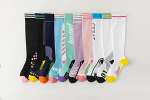 Detail view of colorful fashion knee high socks featuring sporty stripes and letters.
