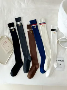 Detailed view of Japanese style knitted over-the-knee socks with stripes and letter embroidery.