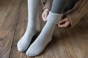 Close-up detail of thick thermal grey winter long socks with fleece lining on wooden floor.