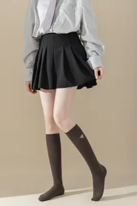 Vue détaillée de la jupe plissée style miu, chemise rayée et chaussettes brodées.