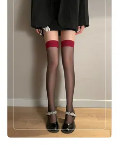 Close-up detail of black sheer over-the-knee stockings with stylish red top trim and fit.