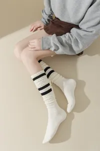 Detailed shot of knitted striped slouch socks in white and black worn by model, cozy fit.