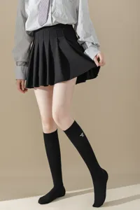 Chaussettes hautes noires avec delicate broderie d'abeille, bonneterie chic et confortable.