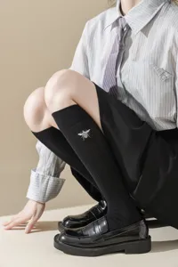 Vue détaillée de chaussettes hautes noires pour femmes avec broderie d'abeille et côtes.