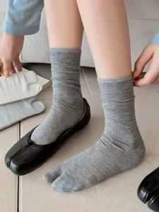 Details of breathable solid color split toe mid tube socks worn with tabi flats indoors.