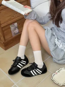 Black and white casual sneakers paired with white mid-tube socks for stylish daily wear.