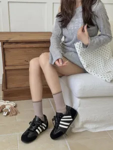 Detail shot of women's solid color casual mid tube socks paired with stylish black sneakers.