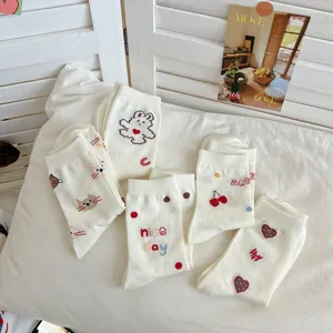 Detail shot of cute Japanese style white cotton socks with bear and cherry embroidery patterns.