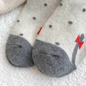 Détail de chaussettes en laine à pois avec adorable motif de chat et texture douce et chaude.