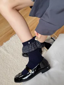 Detail view of women's blue-grey mid-calf socks featuring chic plaid ruffles and delicate pearl accents.