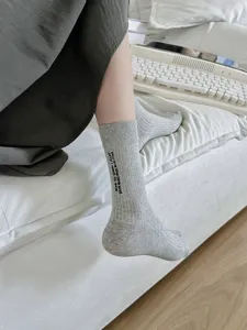 Dettaglio calze a tubo medio a coste grigie con elegante ricamo di lettere e morbido cotone.