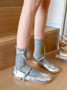 Stylish grey mid-tube socks with delicate ruffled edges and lovely bow ribbons. Close-up detail view.