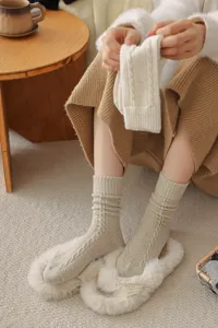 Dettaglio di calze in lana a trecce accoglienti, calzini invernali crema calzati ai piedi.