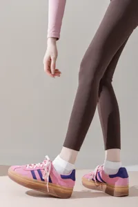 Detailed view of trendy pink platform sneakers paired with white socks and brown leggings.