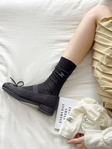Detail view of sweet bow embroidered women mesh socks paired with stylish ballet flats.