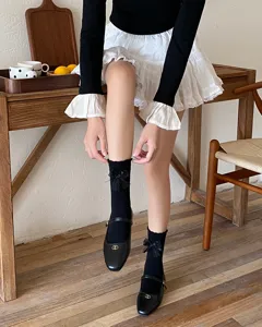 Sweet black mid-calf socks for women featuring delicate lace bow details, perfect for cute JK style.