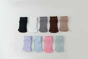 Detail view of multi-color open-toe five-finger yoga and pilates grip socks for women.