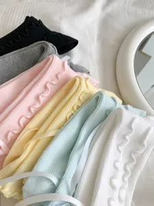 Close-up detail of sweet ruffled mid-calf socks with delicate ribbon bows in multiple soft colors.