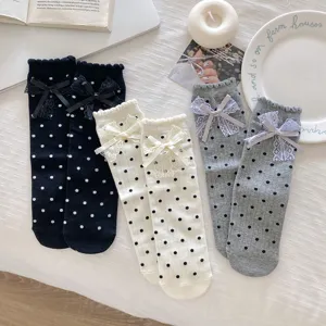 Detail shot of cute polka dot mid-tube socks featuring delicate lace bows and sweet ruffles.