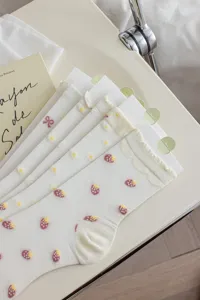 Detailed view of cute white mid-tube socks featuring delicate strawberry and daisy patterns.