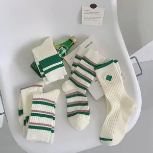 Detailed shot of green striped mid-tube socks with clover embroidery, cozy college style.